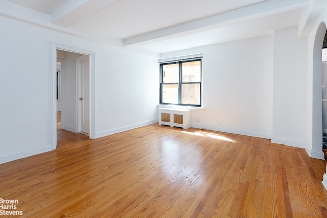 235 W End Ave Unit 3C, New York City, NY 10023 - empty room with radiator, arched walkways, beamed ceiling, light wood-type flooring, and baseboards