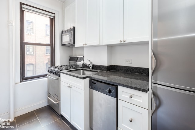 235 W End Ave Unit 3C, New York City, NY 10023 - kitchen with stainless steel appliances, a sink, white cabinets, dark stone countertops, and dark tile patterned flooring