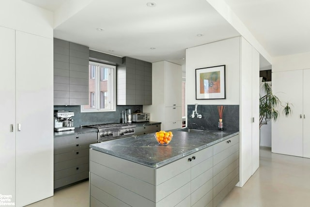 101 W 79th St Unit 14E, New York City, NY 10024 - kitchen featuring decorative backsplash, a sink, stove, modern cabinets, and a peninsula