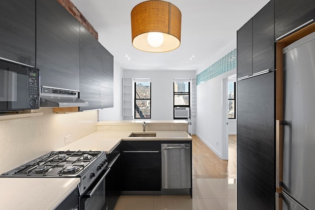 64 Macdougal St Unit 15, New York City, NY 10012 - kitchen with black microwave, under cabinet range hood, range with gas cooktop, dark cabinetry, and freestanding refrigerator