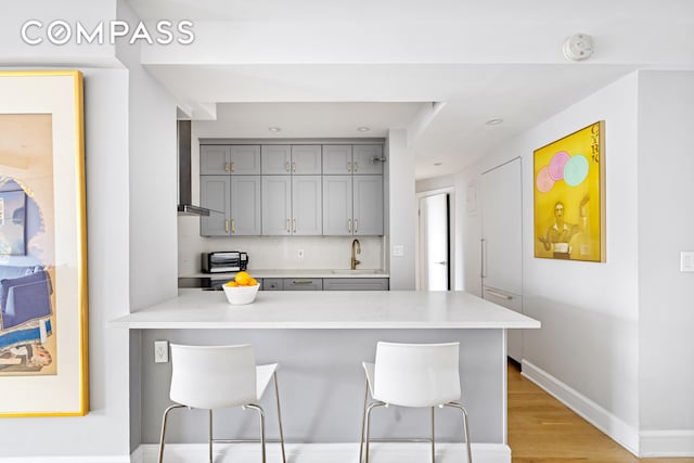 80 E End Ave Unit 17C, New York City, NY 10028 - kitchen with gray cabinets, a peninsula, a kitchen breakfast bar, light countertops, and a sink
