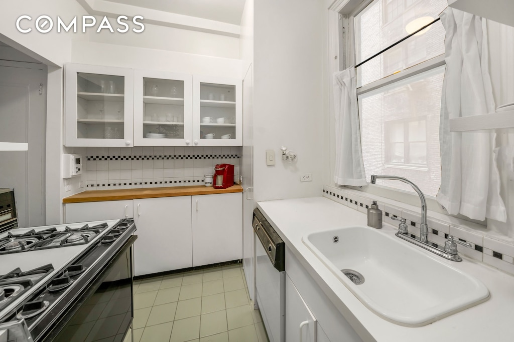 1060 Park Ave Unit 3A, New York City, NY 10128 - kitchen featuring gas stove, dishwasher, backsplash, white cabinets, and light tile patterned floors