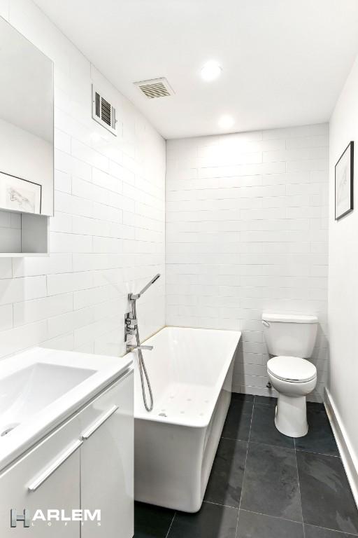 2022 Madison Ave, New York City, NY 10035 - bathroom featuring tile walls, a garden tub, toilet, vanity, and tile patterned flooring