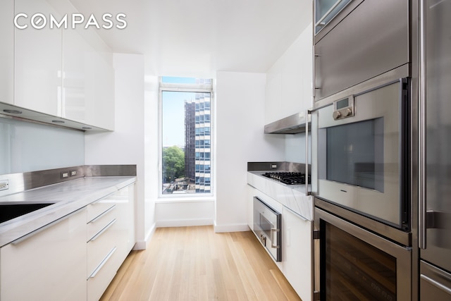 400 E 67th St Unit 7G, New York City, NY 10065 - kitchen featuring modern cabinets, light wood-type flooring, white cabinets, and light countertops