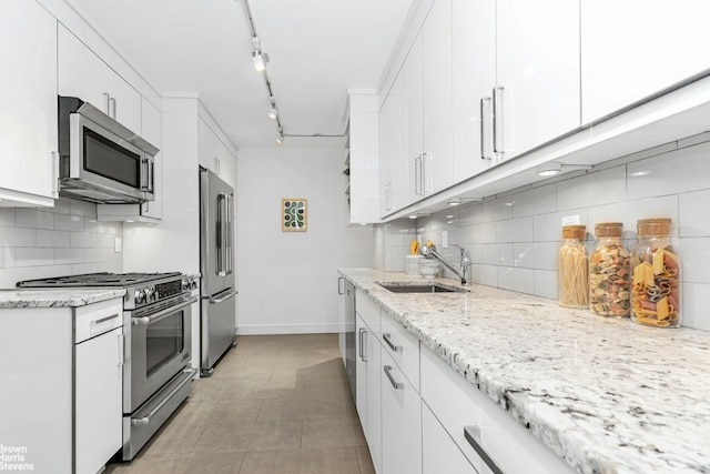 501 E 79th St Unit 5A, New York City, NY 10075 - kitchen featuring appliances with stainless steel finishes, a sink, white cabinets, decorative backsplash, and light stone countertops