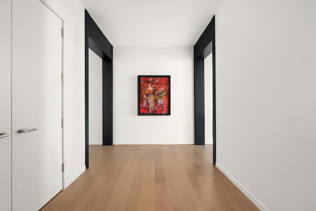 hall with light wood-type flooring and baseboards