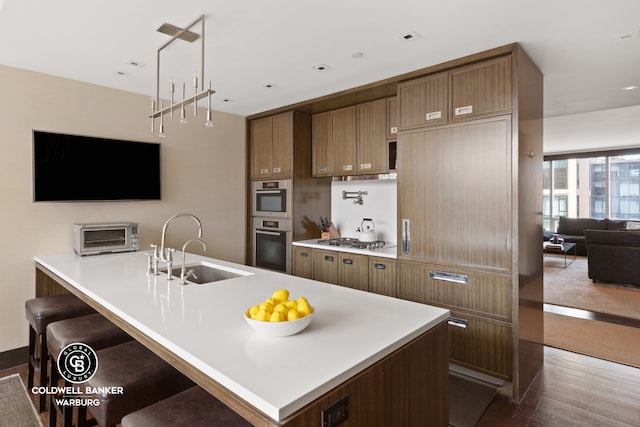 151 E 85th St Unit 17J, New York City, NY 10028 - kitchen with appliances with stainless steel finishes, a sink, light countertops, dark wood finished floors, and a kitchen breakfast bar