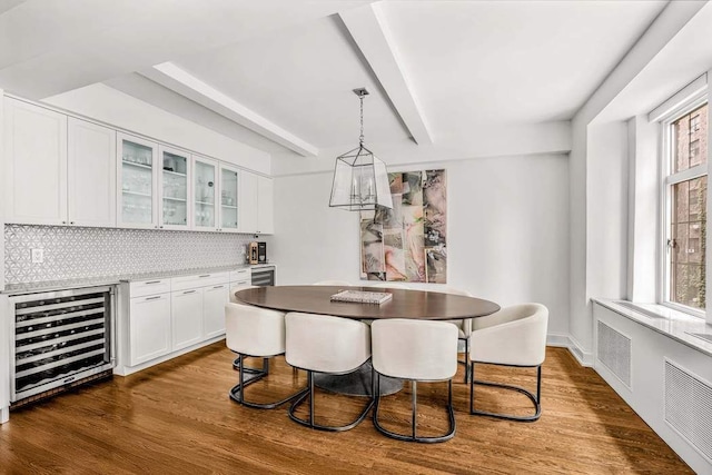 dining space featuring beverage cooler, beam ceiling, and dark wood finished floors
