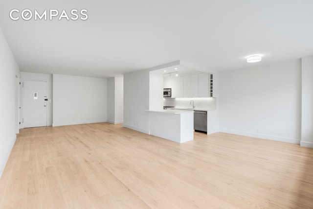 205 W End Ave Unit 15H, New York City, NY 10023 - unfurnished living room with light wood-type flooring, baseboards, and a sink