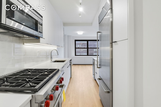 205 W End Ave Unit 15H, New York City, NY 10023 - kitchen with premium appliances, a sink, light wood-style floors, modern cabinets, and white cabinets