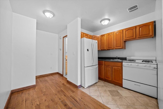53 Woods Place, New York City, NY 11226 - kitchen with white appliances, a sink, brown cabinets, and dark countertops