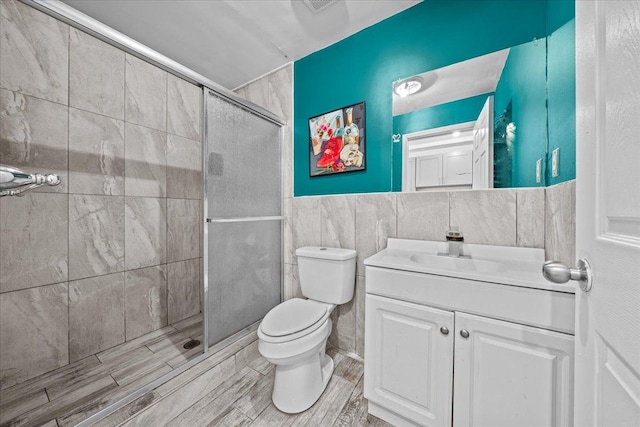 53 Woods Place, New York City, NY 11226 - full bath featuring tile walls, toilet, vanity, a shower stall, and wood finished floors
