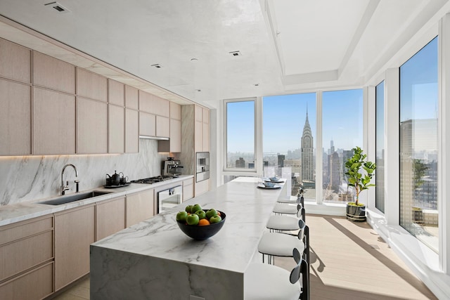 kitchen with a sink, light stone counters, a view of skyline, a center island, and wine cooler
