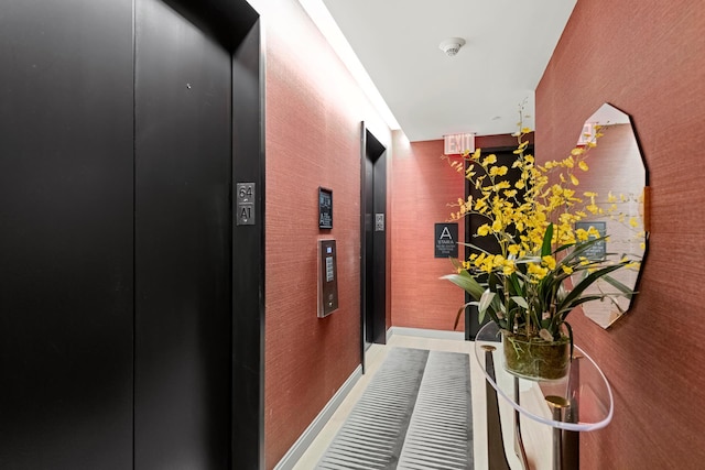 hallway featuring elevator and baseboards