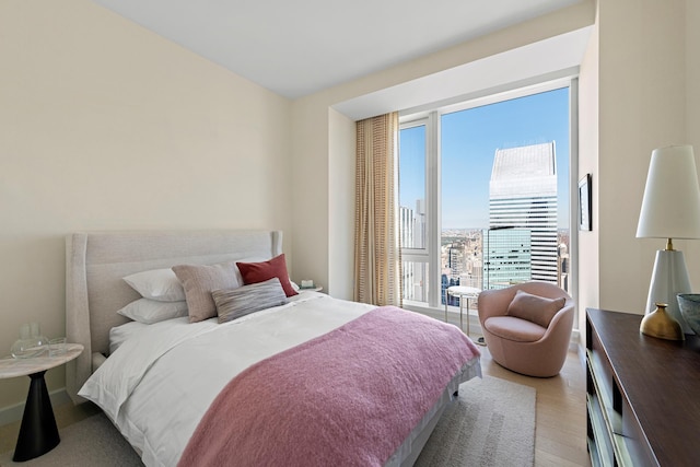bedroom with light wood finished floors and a city view