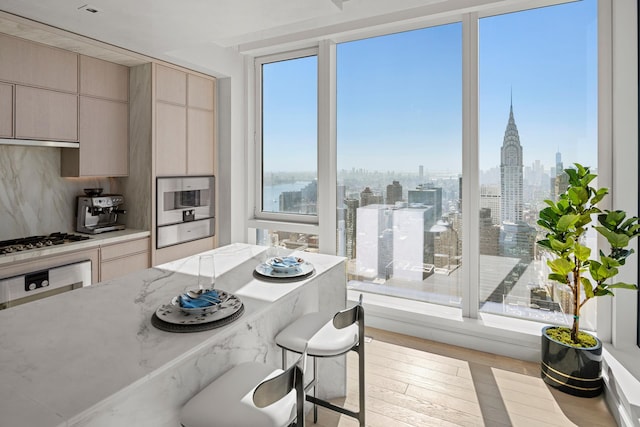 kitchen featuring stainless steel gas cooktop, wood finished floors, a breakfast bar, under cabinet range hood, and a view of skyline