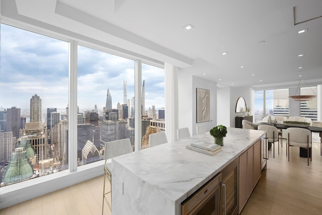 138 E 50th St Unit 68, New York City, NY 10022 - kitchen with light wood-style flooring, light stone counters, stainless steel microwave, a center island, and open floor plan