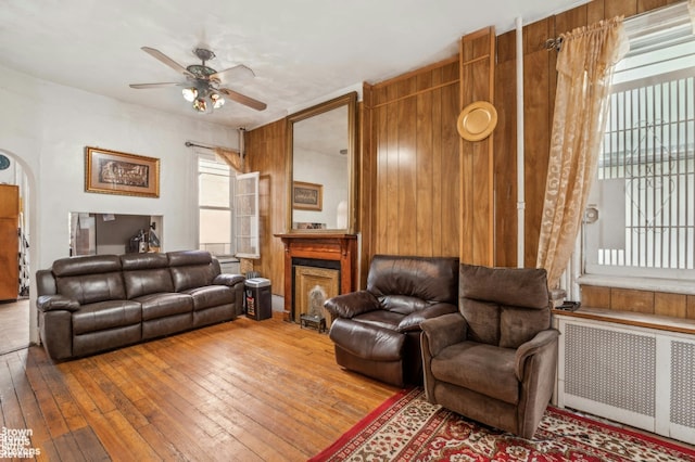 7 Sylvan Ct, New York City, NY 10035 - living room with radiator heating unit, ceiling fan, a fireplace, hardwood / wood-style floors, and wooden walls