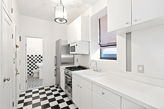 kitchen with white microwave, gas stove, dark floors, light countertops, and a sink
