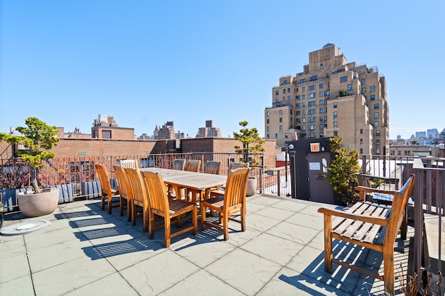 view of patio featuring a view of city, a balcony, and outdoor dining area