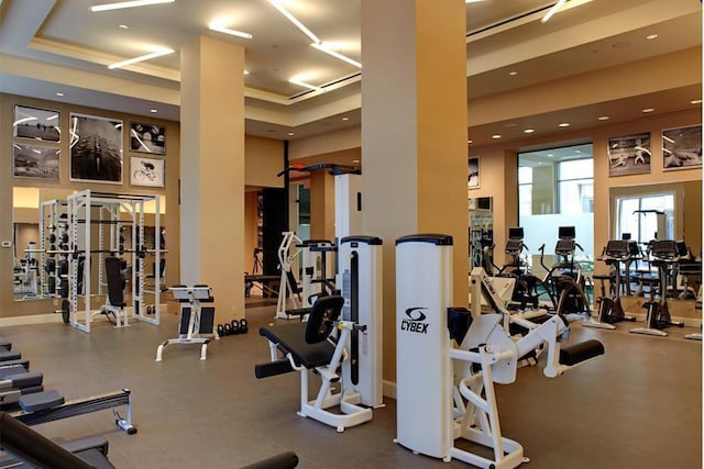 workout area featuring a high ceiling, a tray ceiling, and recessed lighting