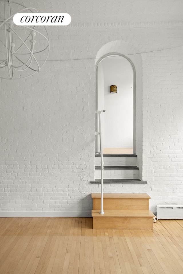 detailed view of arched walkways, wood finished floors, brick wall, and baseboard heating