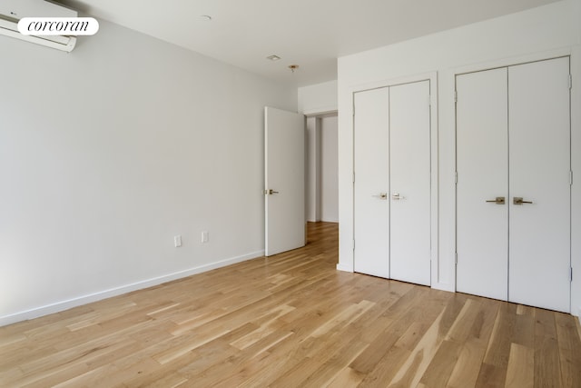 311 Hart St Unit 1A, New York City, NY 11206 - unfurnished bedroom with a wall unit AC, light wood-style flooring, and multiple closets