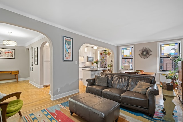 living room with arched walkways, baseboards, and ornamental molding