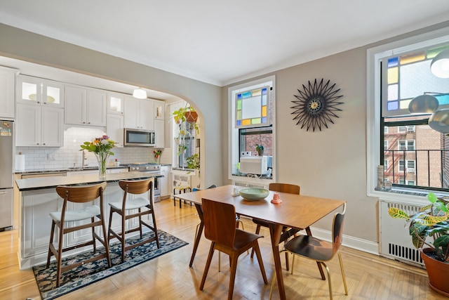 dining area with radiator, arched walkways, and baseboards