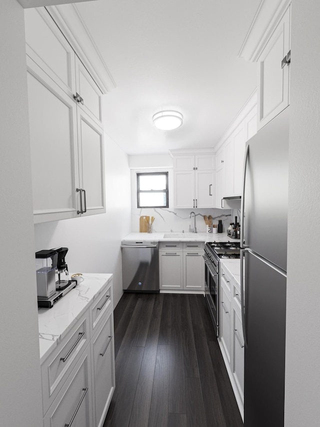 kitchen featuring stainless steel appliances, white cabinets, dark wood-style flooring, light stone countertops, and a sink