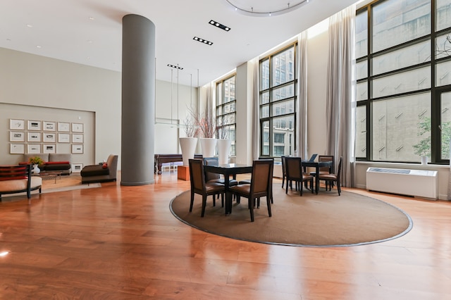 dining area with radiator, a towering ceiling, and wood finished floors