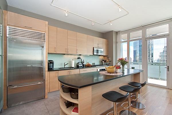 kitchen with stainless steel appliances, dark countertops, a sink, a kitchen bar, and backsplash
