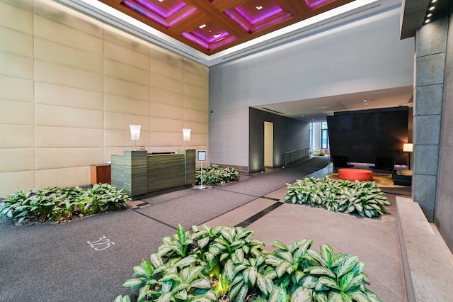building lobby featuring coffered ceiling, a high ceiling, and beam ceiling