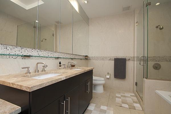 bathroom with tile walls, double vanity, a shower stall, toilet, and a garden tub