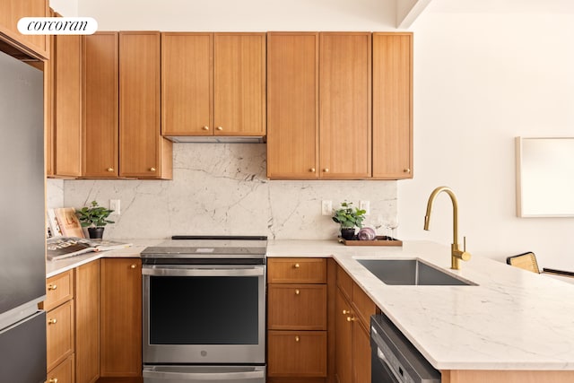 kitchen featuring stainless steel appliances, a sink, a peninsula, and backsplash