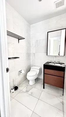 75 Wall St Unit 18Fg, New York City, NY 10005 - half bathroom featuring tile walls, toilet, and vanity