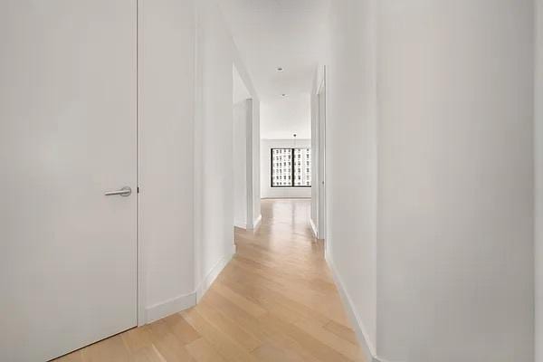 75 Wall St Unit 18Fg, New York City, NY 10005 - hall featuring light wood-style floors and baseboards