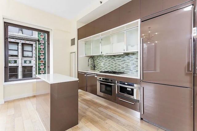 75 Wall St Unit 18Fg, New York City, NY 10005 - kitchen featuring stainless steel appliances, tasteful backsplash, light countertops, and a sink