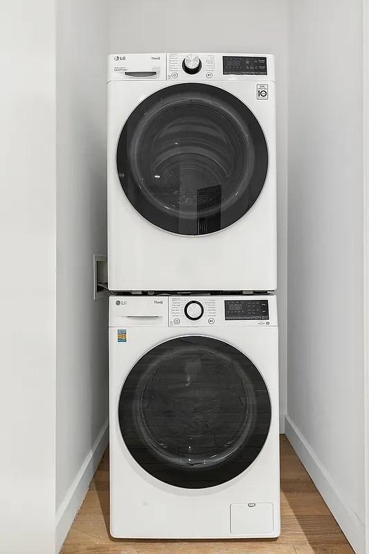 75 Wall St Unit 18Fg, New York City, NY 10005 - washroom with stacked washer / drying machine, wood finished floors, and baseboards