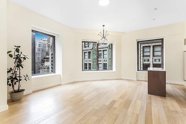 75 Wall St Unit 18Fg, New York City, NY 10005 - unfurnished dining area with light wood finished floors, a chandelier, and baseboards