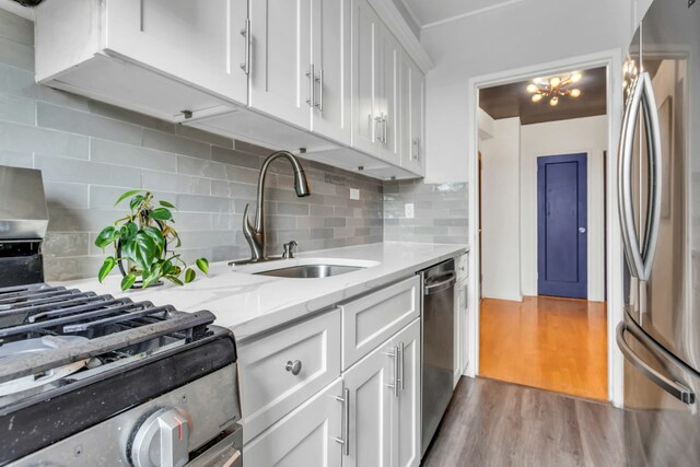88-01 35th Ave Unit 5F, New York City, NY 11372 - kitchen with appliances with stainless steel finishes, a sink, white cabinets, wood finished floors, and decorative backsplash