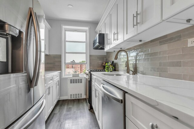 88-01 35th Ave Unit 5F, New York City, NY 11372 - kitchen with appliances with stainless steel finishes, a sink, radiator heating unit, tasteful backsplash, and white cabinets