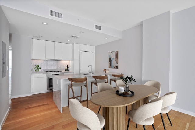 dining room featuring light wood-type flooring, baseboards, and recessed lighting