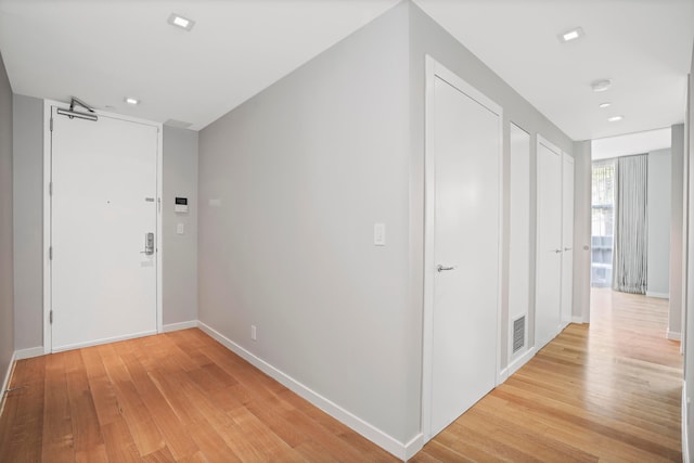 hall featuring light wood-style flooring, baseboards, and recessed lighting