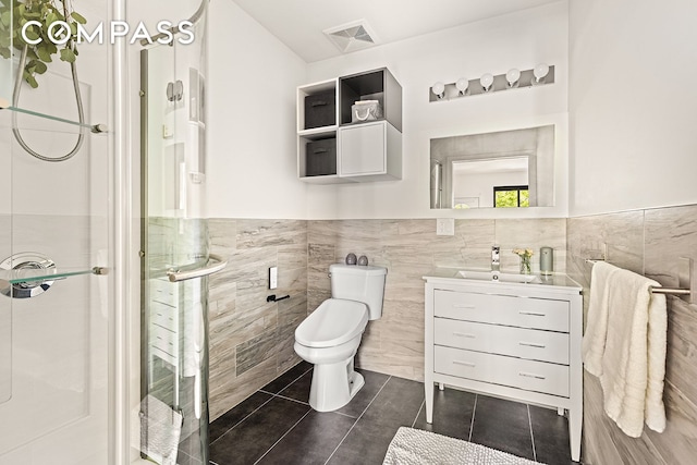 495 Rutland Rd Unit 1, New York City, NY 11203 - bathroom featuring tile walls, vanity, a stall shower, tile patterned floors, and a wainscoted wall