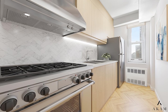 kitchen with appliances with stainless steel finishes, radiator heating unit, exhaust hood, a sink, and backsplash