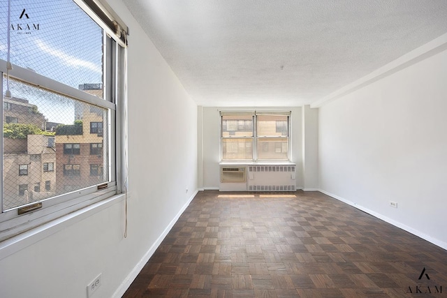 empty room featuring healthy amount of natural light, baseboards, and a textured ceiling