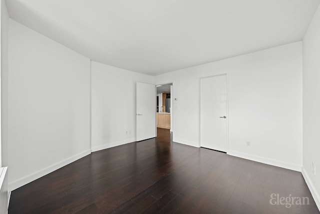 unfurnished room with dark wood-style flooring and baseboards