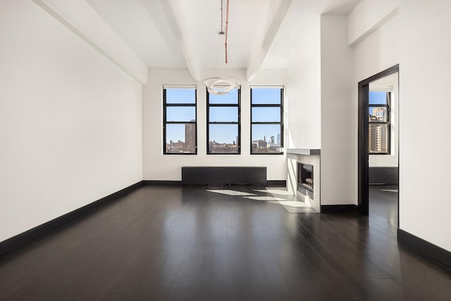 60 Broadway Unit 7K, New York City, NY 11249 - unfurnished living room with baseboards, dark wood-style flooring, beam ceiling, and a fireplace with flush hearth