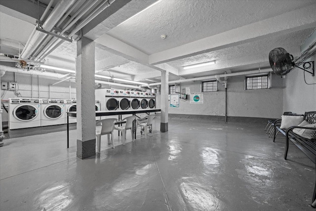 basement with independent washer and dryer, a textured ceiling, and a textured wall